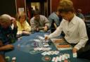 A dealer in a white shirt deals cards to players seated around a blue blackjack table at a casino.