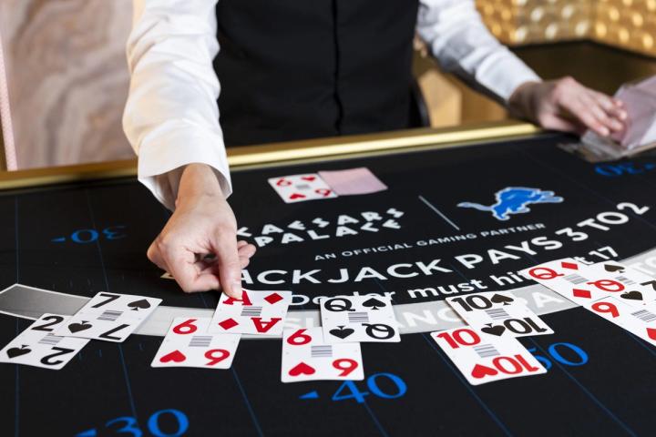 Close-up of a dealer's hands dealing cards on a Caesars Palace blackjack table.