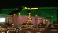 The MGM Grand hotel and casino in Las Vegas illuminated in green at night, featuring its iconic golden lion statue.