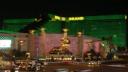 The MGM Grand hotel and casino in Las Vegas illuminated in green at night, featuring its iconic golden lion statue.