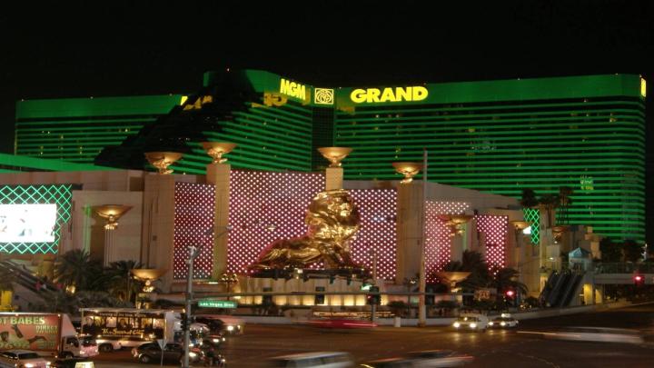 The MGM Grand hotel and casino in Las Vegas illuminated in green at night, featuring its iconic golden lion statue.