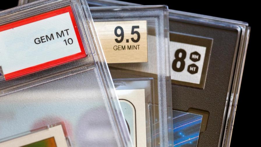 Close-up of three graded trading cards in plastic slabs, showing grades of GEM MT 10, 9.5 GEM MINT, and 8 NM MT.