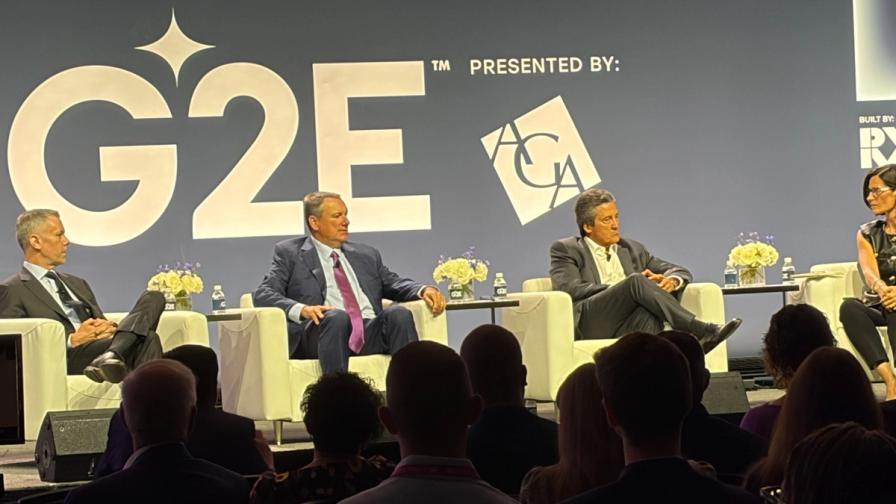 Panelists speak on stage at a G2E conference, with audience members in the foreground.