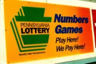 Yellow and orange Pennsylvania Lottery sign reading "Numbers Games Play Here! We Pay Here!