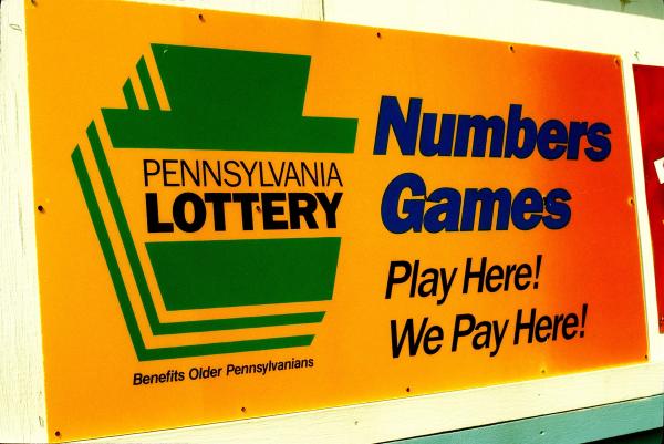 Yellow and orange Pennsylvania Lottery sign reading "Numbers Games Play Here! We Pay Here!