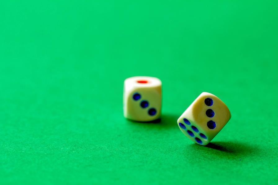 Two white dice with blue and red dots on a vibrant green felt surface.