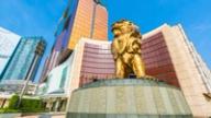A large golden lion statue stands in front of a modern MGM resort building under a clear blue sky.