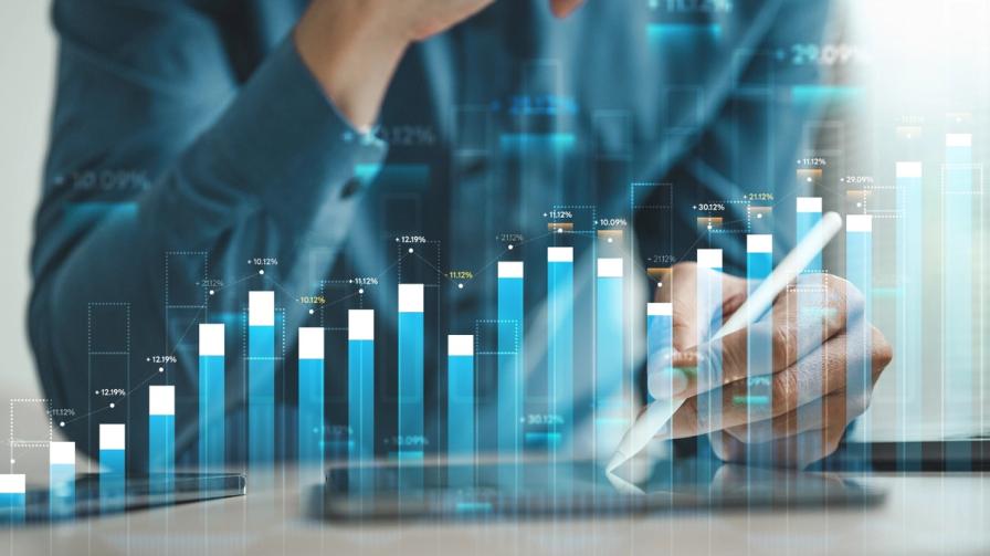 A hand using a stylus on a tablet, overlaid with glowing blue bar charts and financial growth graphs.