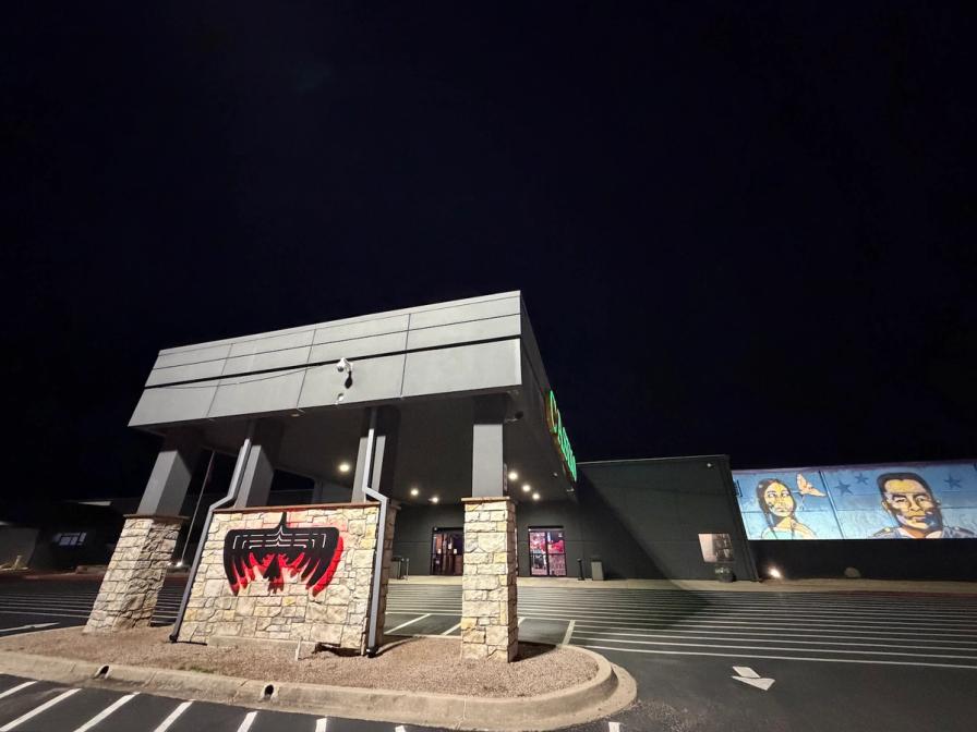 Exterior of a casino at night, featuring a stone entrance with a red bird emblem and a mural of