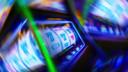 A motion-blurred close-up of spinning slot machine reels showing lucky sevens with vibrant neon lights.