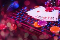 Playing cards and poker chips on a backlit computer keyboard, representing online casino gaming.