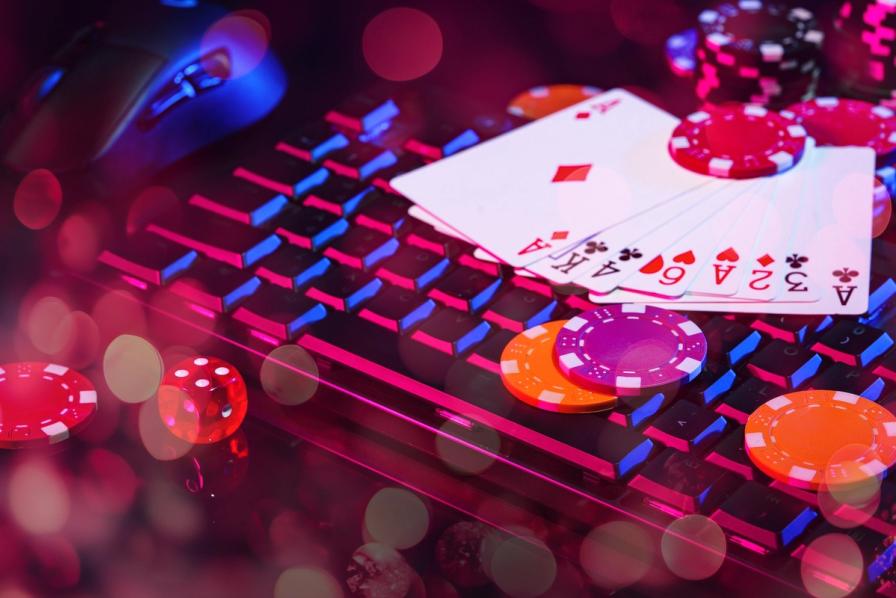 Playing cards and poker chips on a backlit computer keyboard, representing online casino gaming.