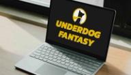 Laptop on a wooden desk displaying the Underdog Fantasy logo and name on a black screen.