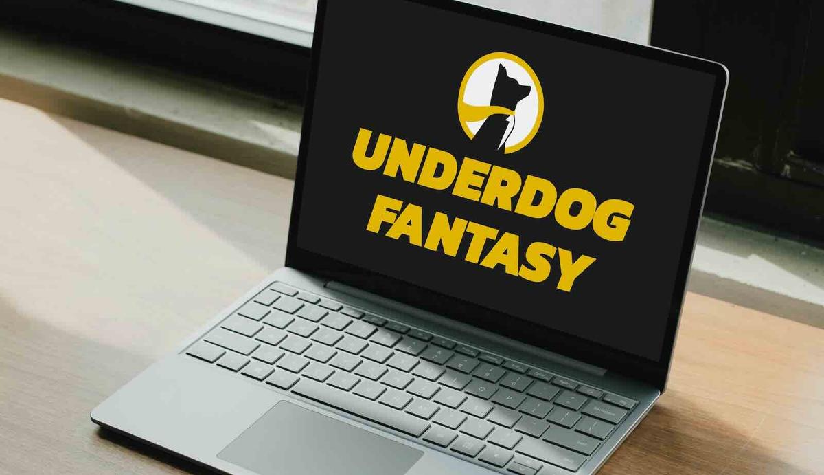 Laptop on a wooden desk displaying the Underdog Fantasy logo and name on a black screen.