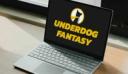 Laptop on a wooden desk displaying the Underdog Fantasy logo and name on a black screen.