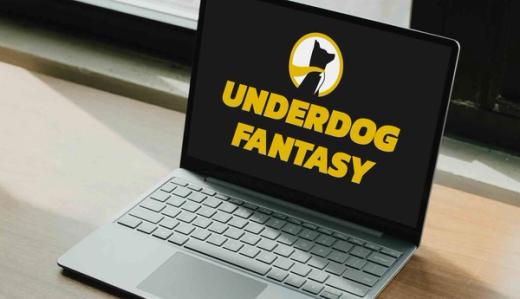 Laptop on a wooden desk displaying the Underdog Fantasy logo and name on a black screen.