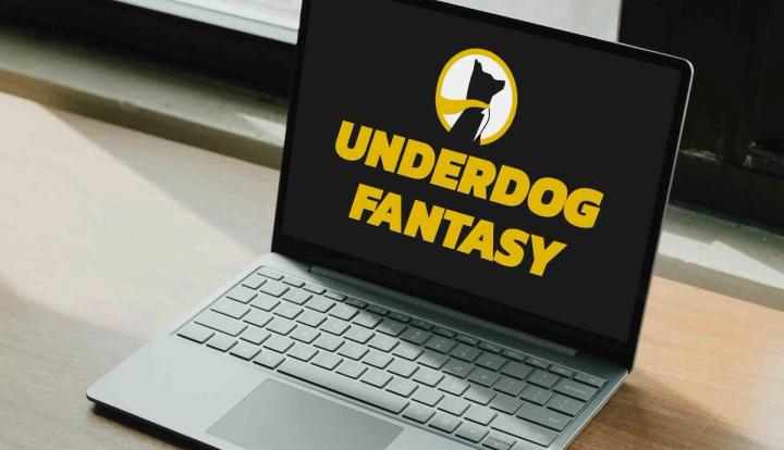Laptop on a wooden desk displaying the Underdog Fantasy logo and name on a black screen.
