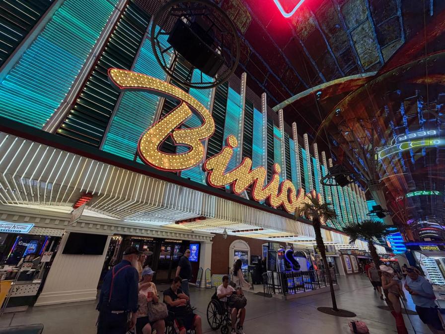 The bright, illuminated Binion's neon sign on Fremont Street in Las Vegas, with pedestrians walking below.
