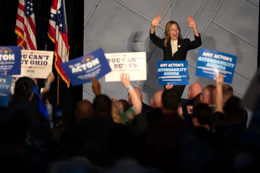Amy Acton waves to a crowd holding campaign signs at an Ohio political rally.