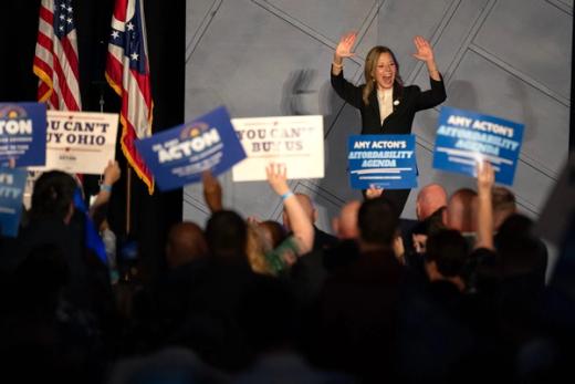 Amy Acton waves to a crowd holding campaign signs at an Ohio political rally.
