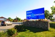 A large blue roadside sign reading "Welcome to Pure Michigan" on a stone base.
