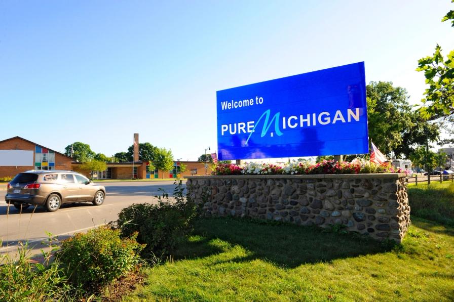 A large blue roadside sign reading "Welcome to Pure Michigan" on a stone base.