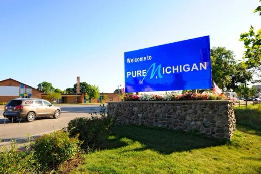 A large blue roadside sign reading "Welcome to Pure Michigan" on a stone base.