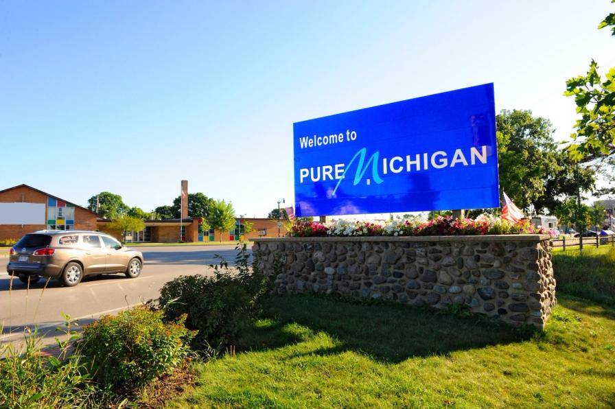 A large blue roadside sign reading "Welcome to Pure Michigan" on a stone base.