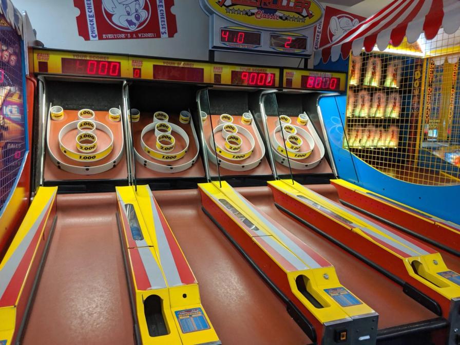 Honolulu - September 15, 2019: Four Skee-Ball tables for play in arcade at Chuck E. Cheese. It is played by rolling a ball up an inclined lane and over a "ball-hop" hump that jumps the ball into bullseye rings. The object of the game is to collect as many points as possible by having the ball fall into holes in the rings which have progressively increasing point values.