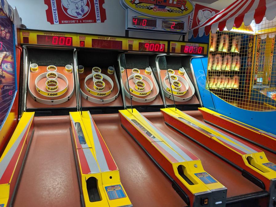 Honolulu - September 15, 2019: Four Skee-Ball tables for play in arcade at Chuck E. Cheese. It is played by rolling a ball up an inclined lane and over a "ball-hop" hump that jumps the ball into bullseye rings. The object of the game is to collect as many points as possible by having the ball fall into holes in the rings which have progressively increasing point values.