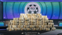 A massive pyramid of bundled $100 bills on a poker table with a World Series of Poker logo in the background.