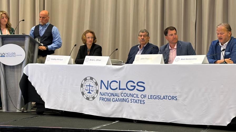 A panel of speakers seated at a table with an NCLGS (National Council of Legislators from Gaming States) banner.