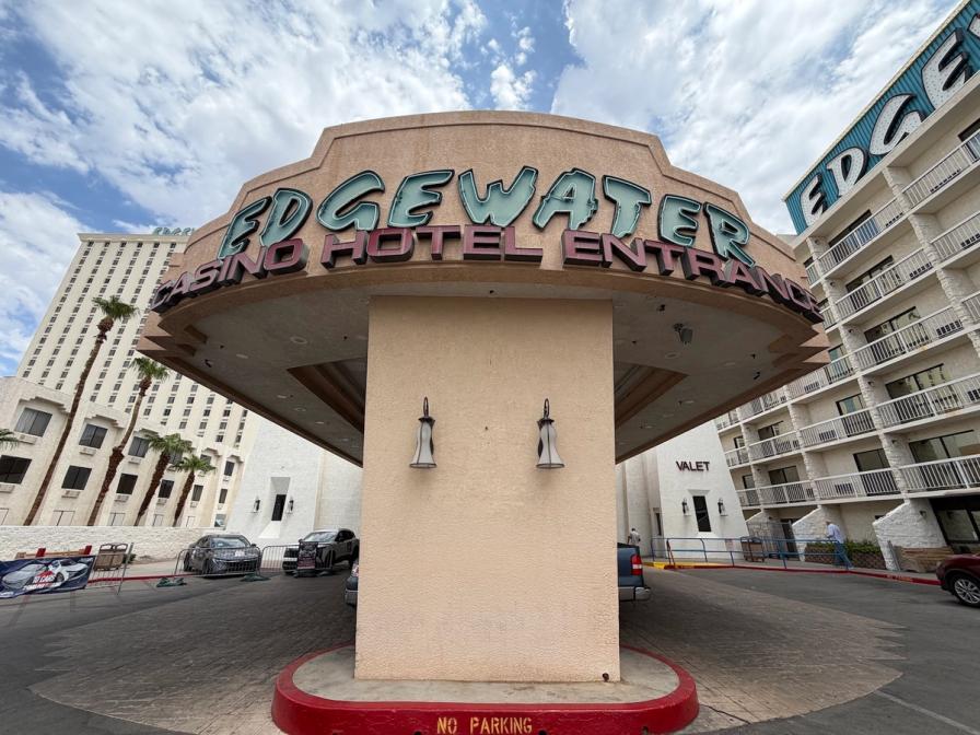 Edgewater Casino Hotel entrance sign on a beige stucco canopy, with hotel buildings in the background.