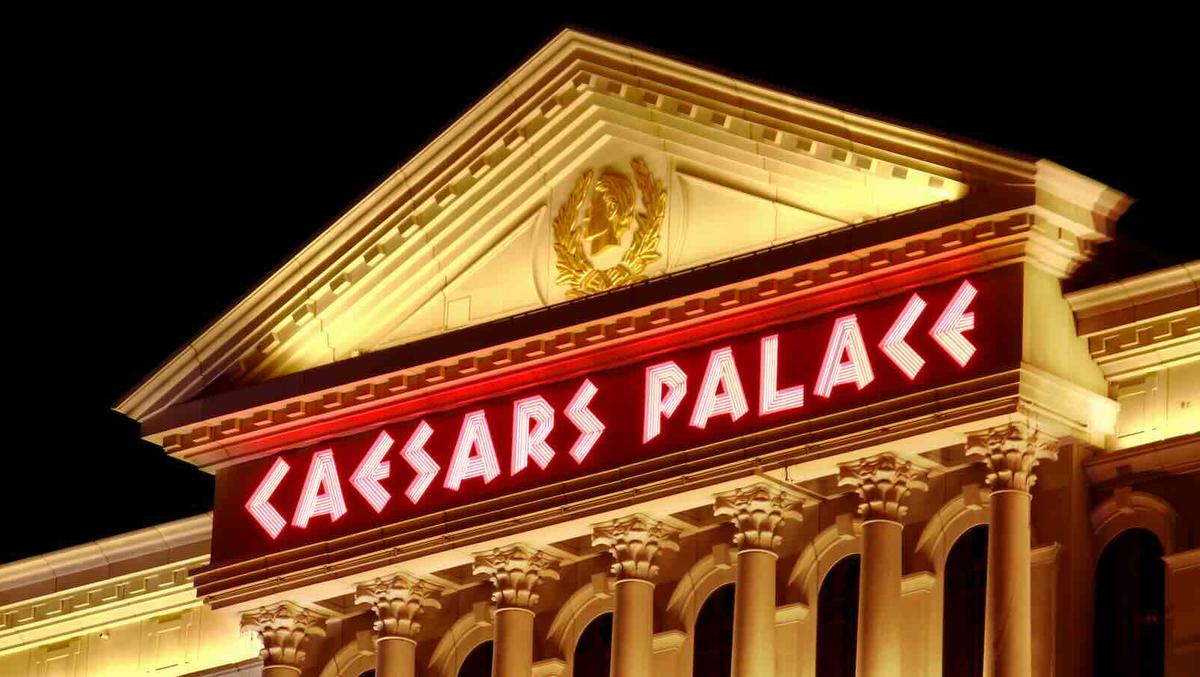 Illuminated Caesars Palace sign on the Roman-style facade of the Las Vegas hotel and casino at night.