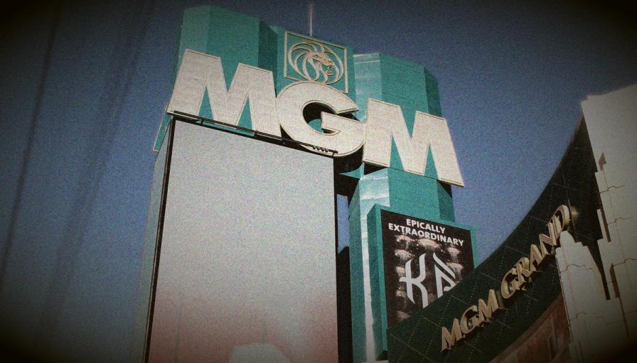 Low-angle shot of the green MGM Grand sign in Las Vegas, featuring large white letters and a billboard for the