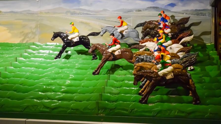 A vintage mechanical horse racing game featuring plastic horses and jockeys on a tiered green track.