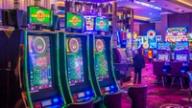 Row of electronic roulette machines glowing on a brightly lit casino floor.