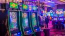Row of electronic roulette machines glowing on a brightly lit casino floor.