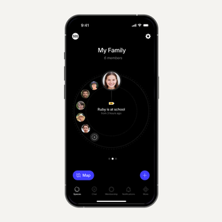 Un teléfono inteligente mostrando una aplicación de seguridad familiar en modo oscuro con un perfil central de "Ruby en la escuela" rodeado por otros miembros de la familia.