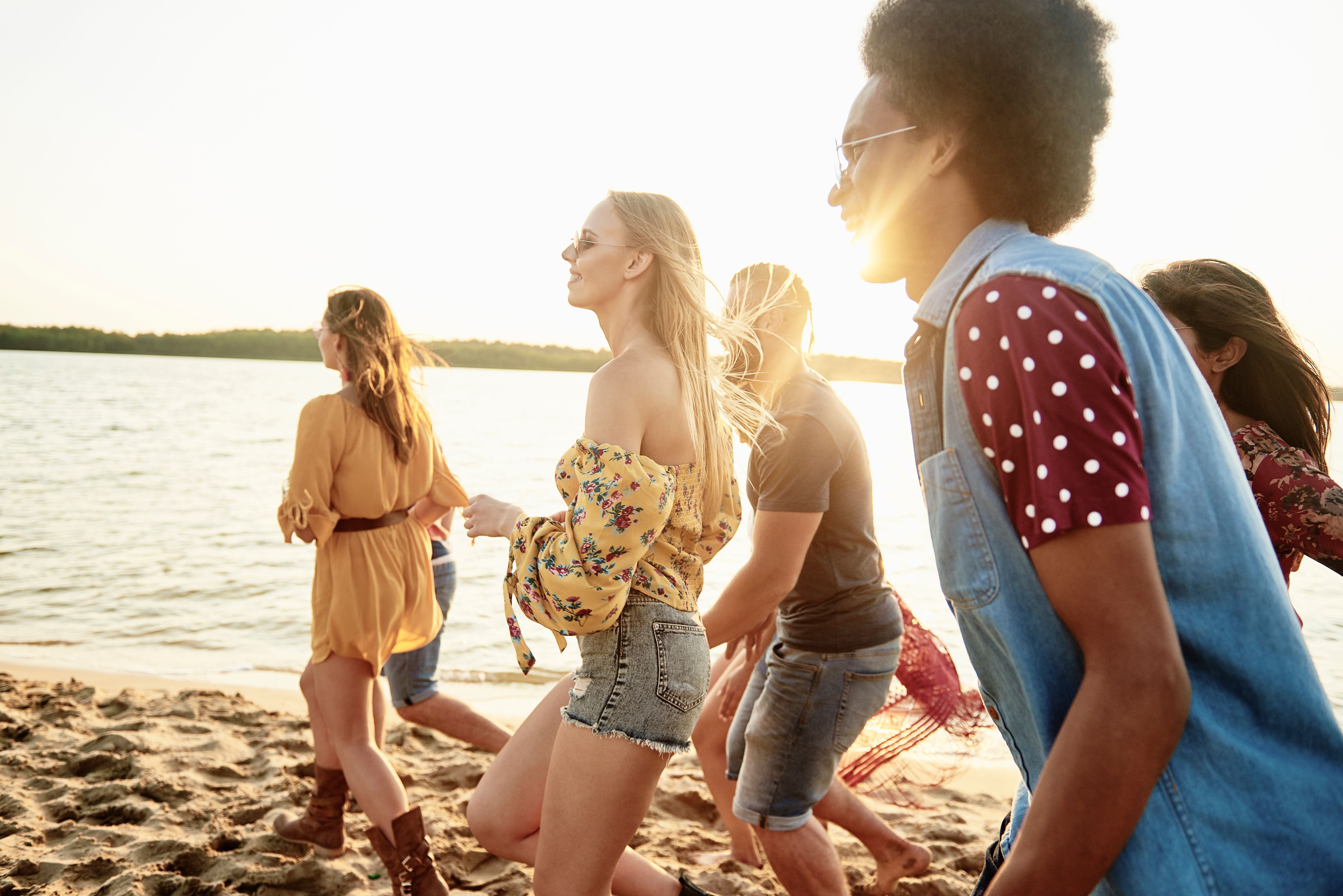 Un grupo de personas caminando por una playa arenosa al atardecer.