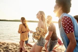 A group of people walking along a sandy beach at sunset.