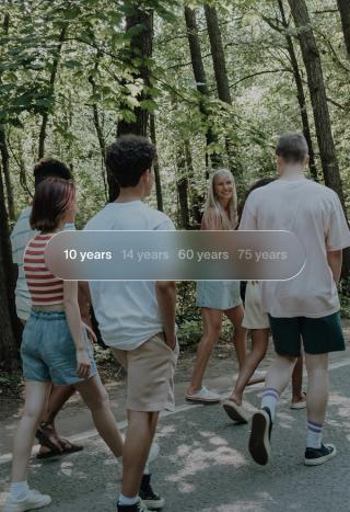 A group of young people walk in a forest, with a translucent overlay showing age options: '10 years' (selected), '14 years', '60 years', '75 years'.