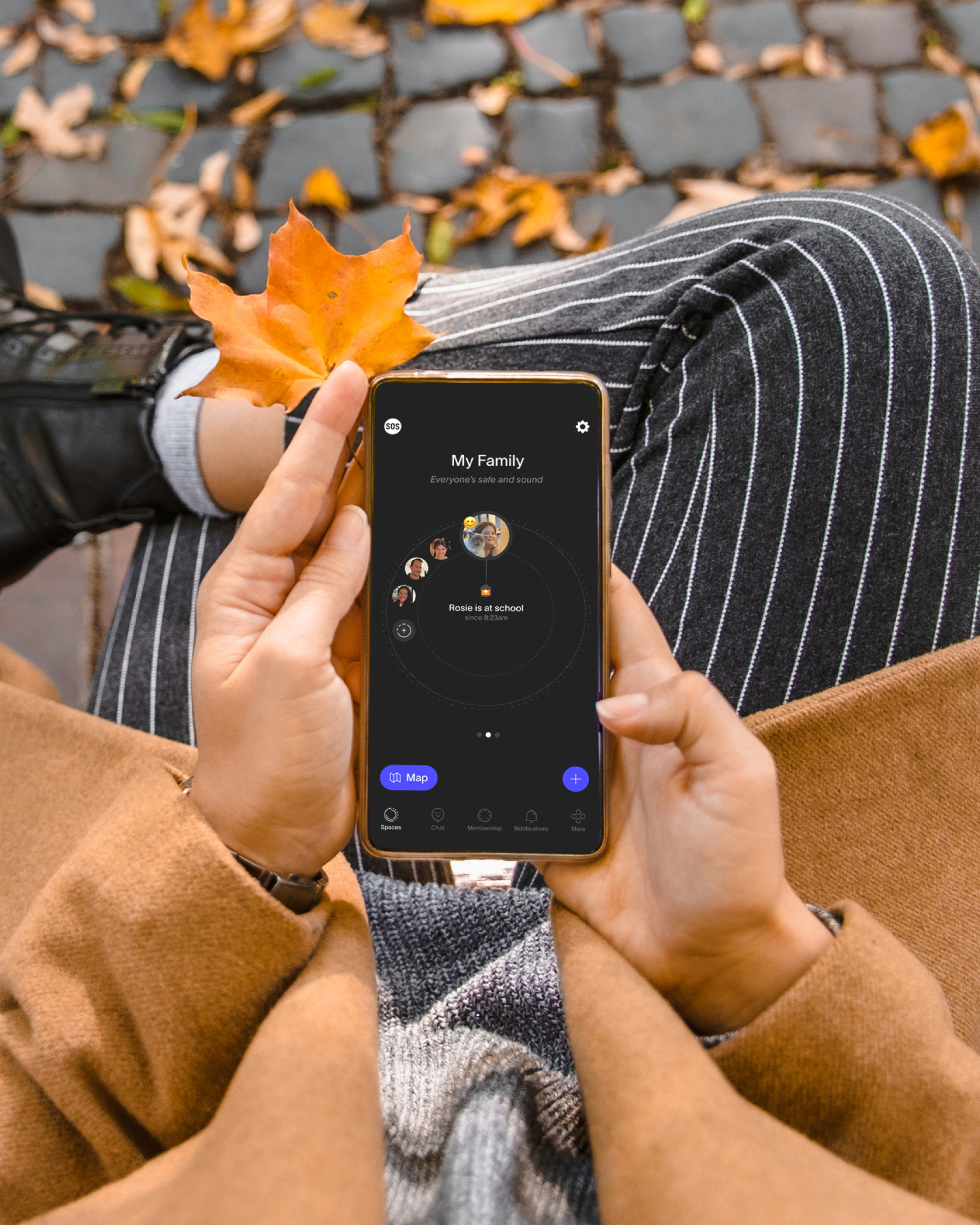 Una mano sostiene un teléfono inteligente que muestra el logotipo de la aplicación SPACETALK rodeado por una disposición circular de pequeñas imágenes.