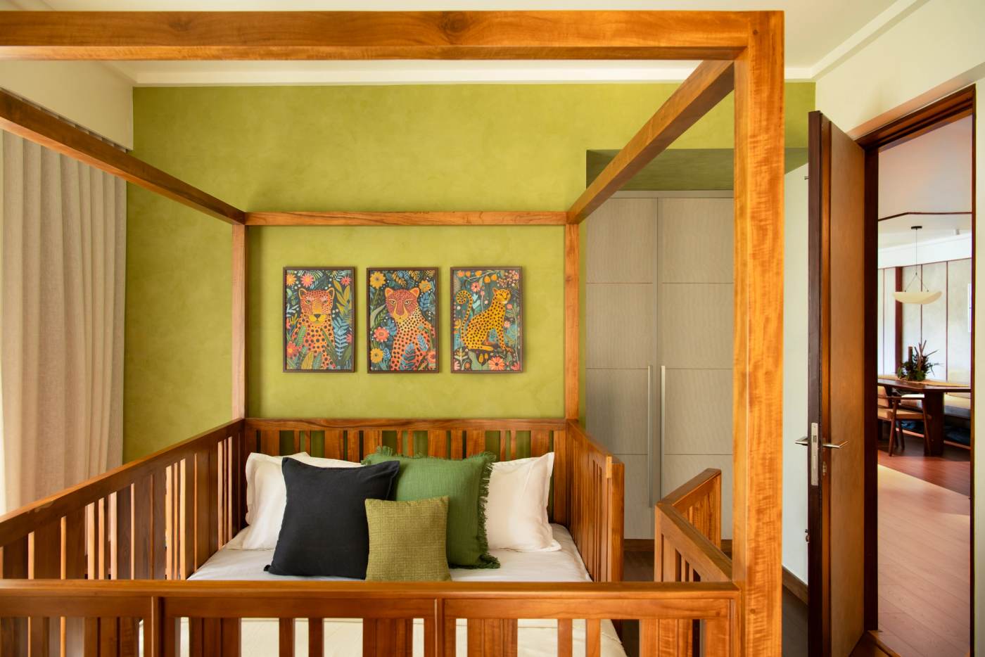 A bedroom in olive green, with a timber four-poster and three painted panels