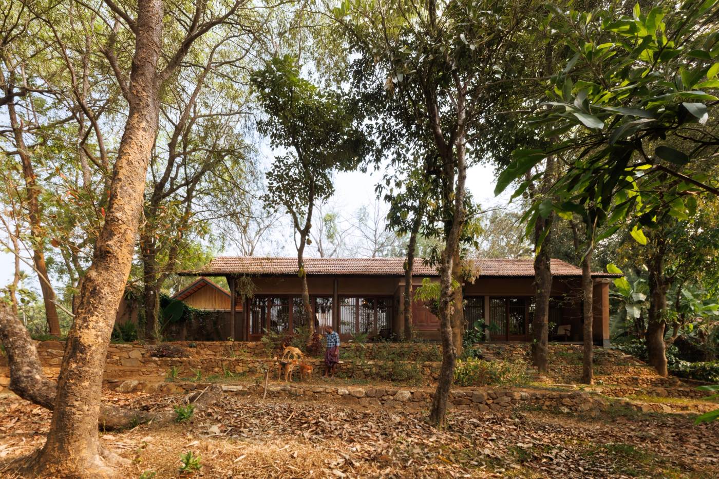 Nelly House seen from the approach, rammed earth walls under a terracotta roof