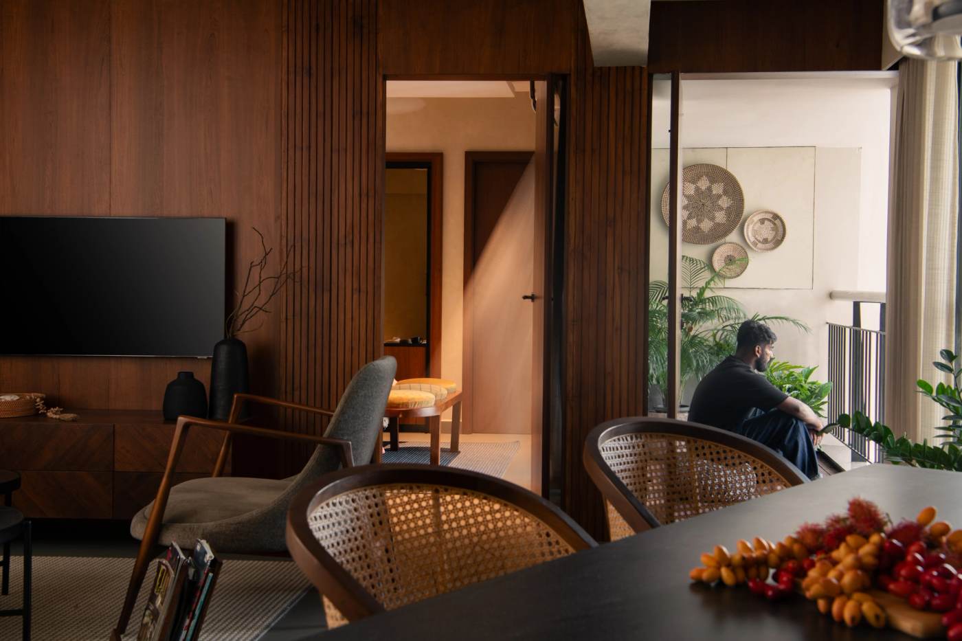 The living room looking out to the balcony, cane chairs drawn up to the table