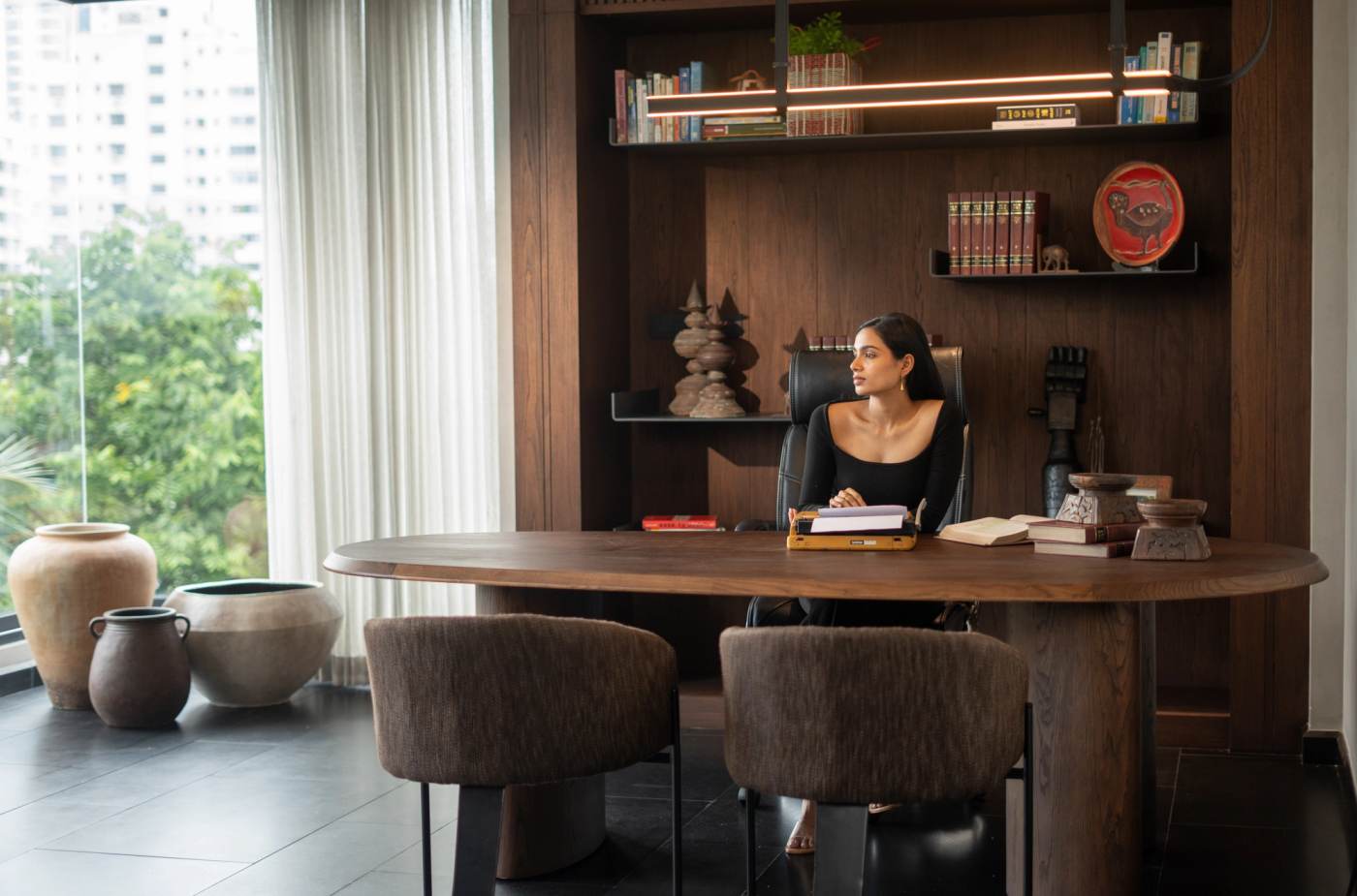 The study, an oval timber desk set against fitted bookshelves