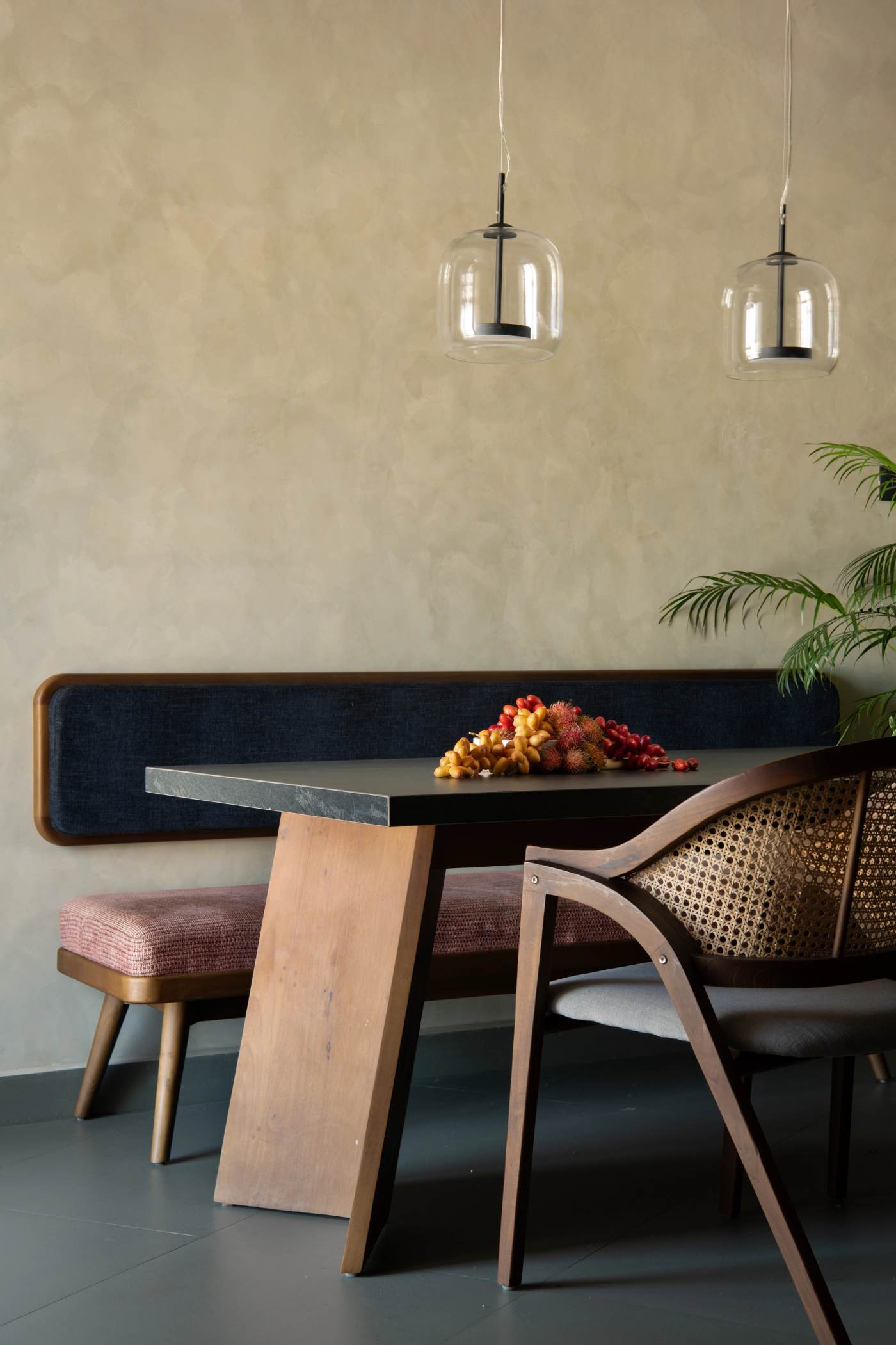 The dining nook, a navy banquette under two glass pendants