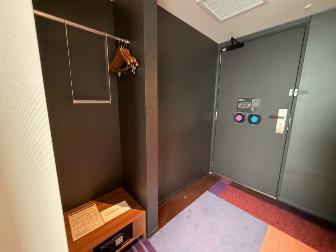 Open wardrobe with a lowered hanging rail and bench near the room entrance