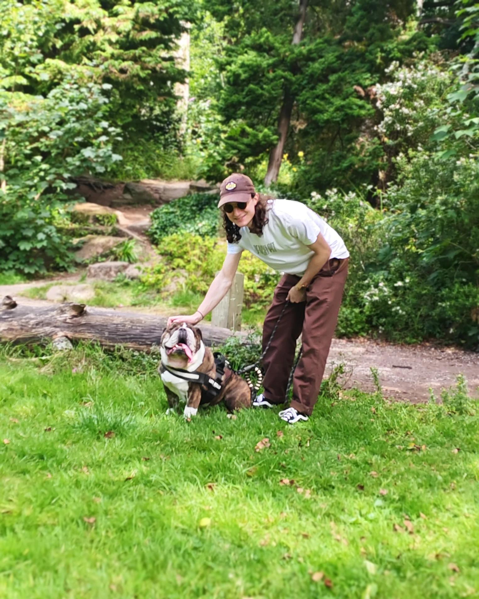 Dan in a Liverpool park, crouching to pat his English bulldog